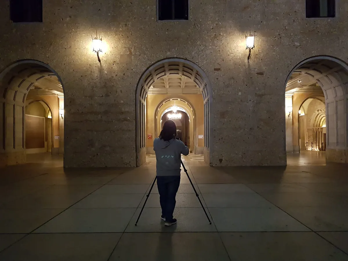 Silhouette of a person framed by an ancient stone archway at sunset